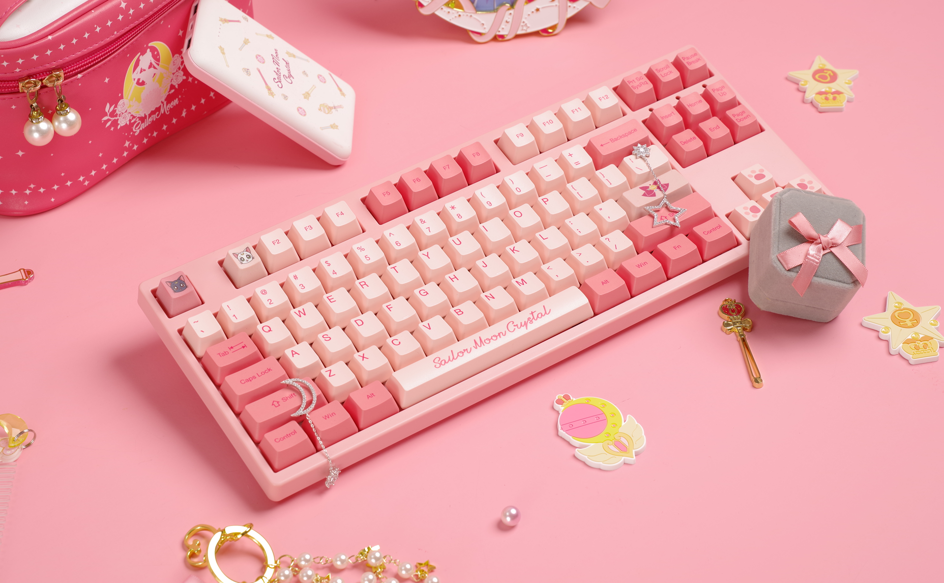 Akko Sailor Moon Crystal 3087 Keyboard surrounded by various pink Sailor Moon-themed accessories on a clean surface